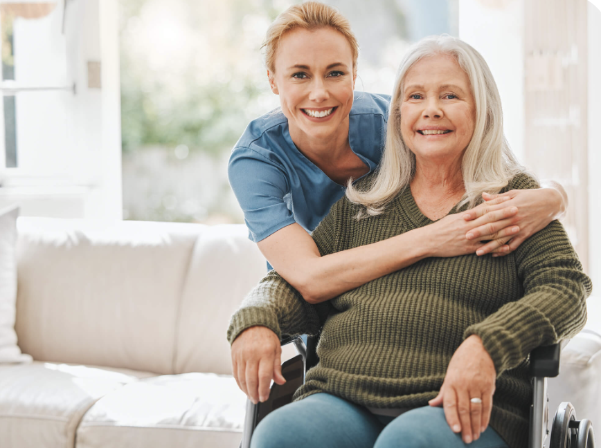 A caregiver embracing an older woman in a wheelchair during an uplifting home-care moment